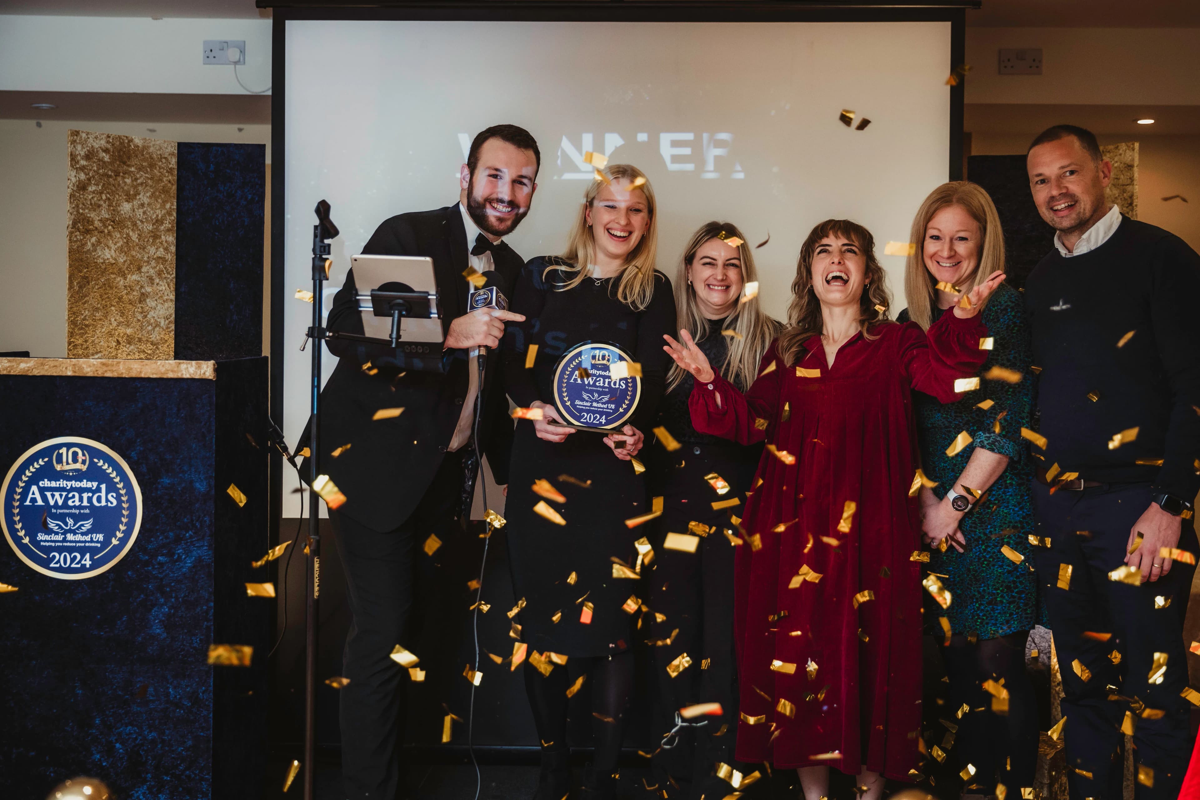 Award winners celebrating on stage with confetti.